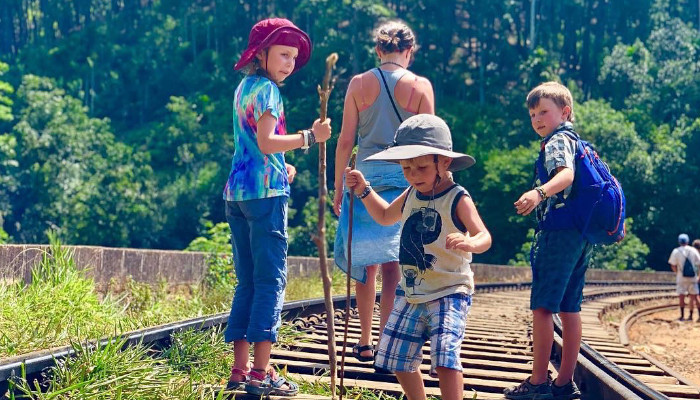 a tourist family walking on a railway track with children